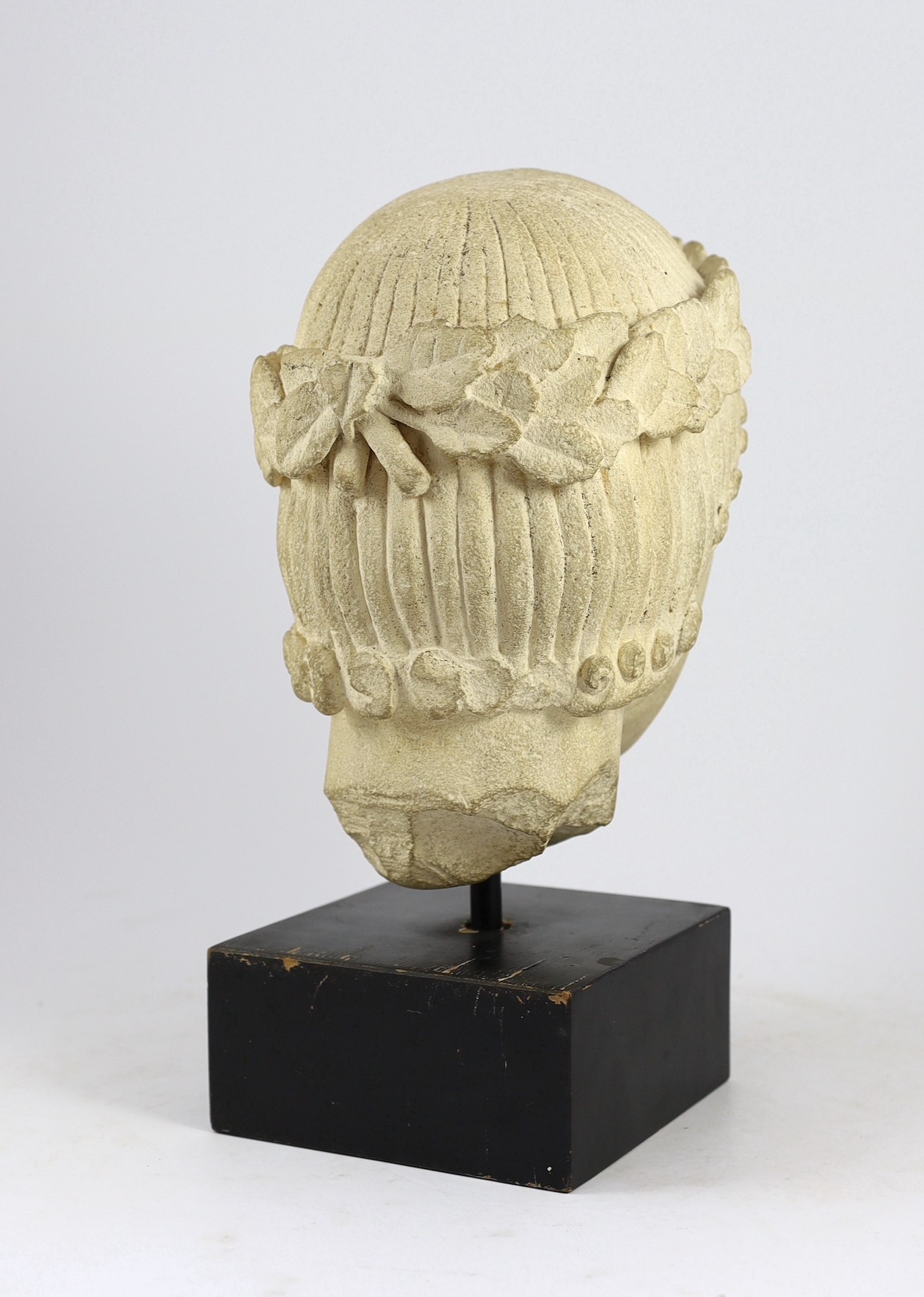 An antique limestone head wearing a laurel wreath diadem, possibly 18th/19th century, 29cm high overall 39cm